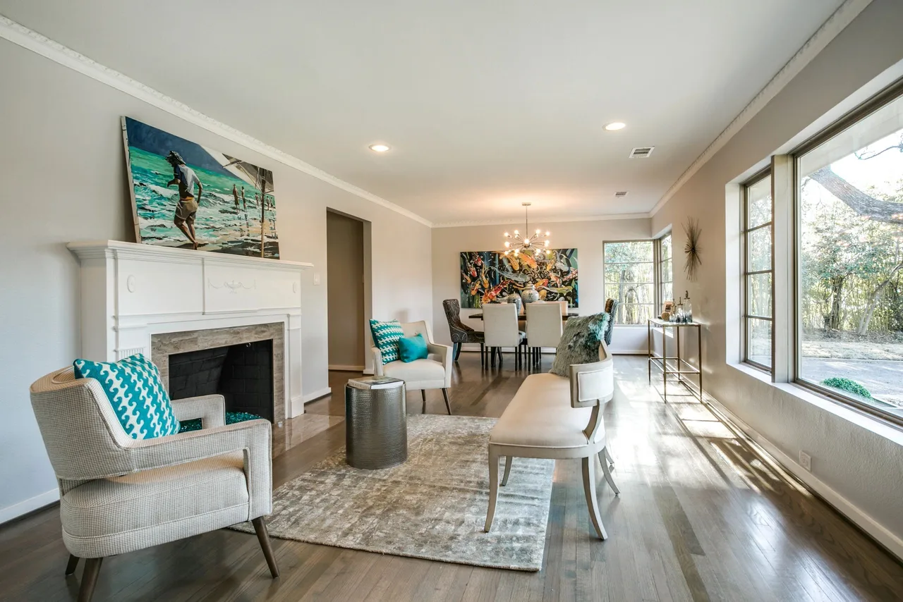 Full-size bright living and dining room with wall of windows, teal accents and a chandelier, the site's cover image.